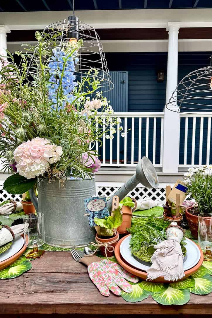 This beautiful garden table features a large galvanized watering can filled with fresh flowers as the centerpiece. 