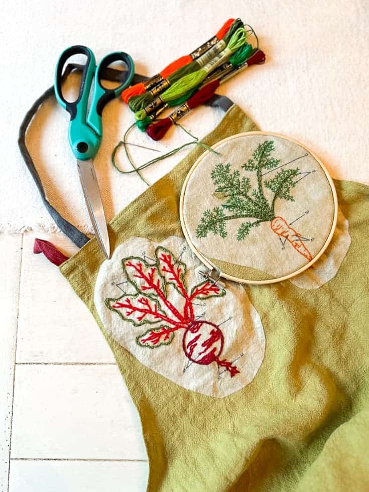 A garden apron that is embroidered with vegetables.