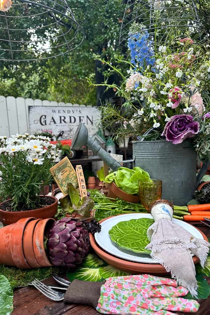 Garden Party Tablescape with fresh flowers and fruit. Silverware in a gardening glove, terra cotta pots and galvanized watering cans. 
