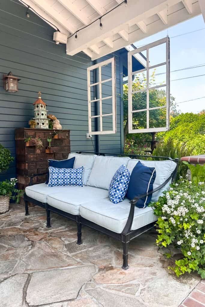 Back porch with a couch and two vintage windows hanging. The perfect California backyard living. 