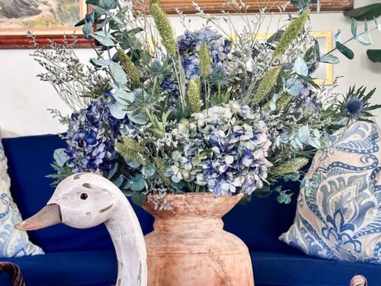 Blue dried hydrangea arrangement in a wooden vase sitting on the coffee table