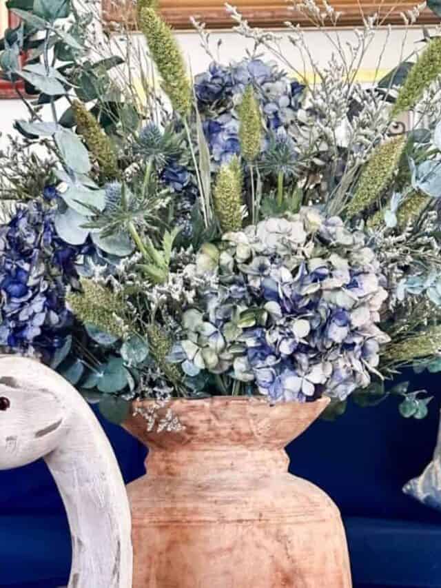 Blue dried hydrangea arrangement in a wooden vase sitting on the coffee table