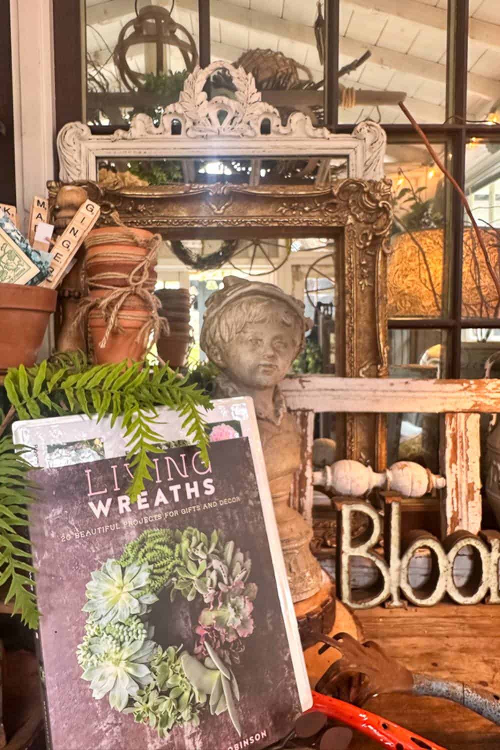 A close-up of the work desk inside the She Shed styled for summer with garden books, antique picture frames, and vintage garden decor