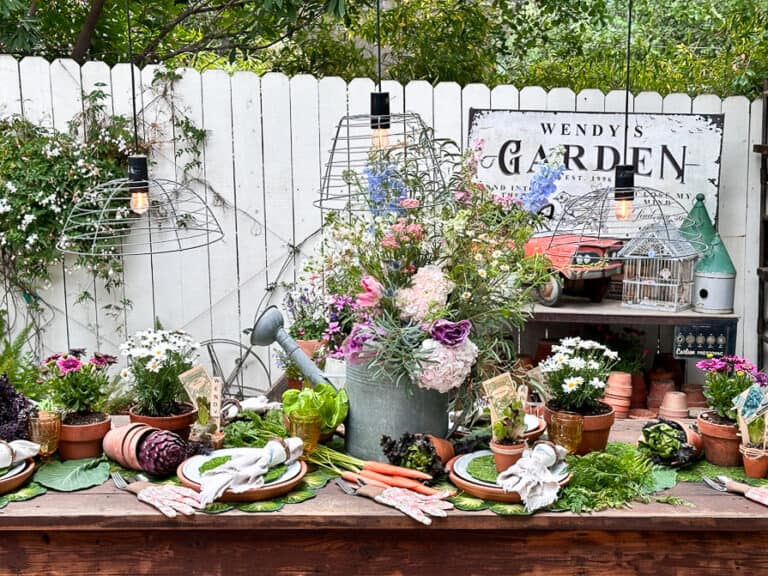 A garden party tablescape set to perfection with fresh flowers, vegetables and other garden decor.