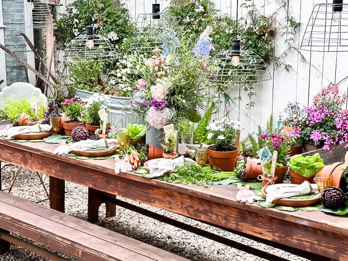 A garden party tablescape set to perfection with fresh flowers, vegetables and other garden decor.