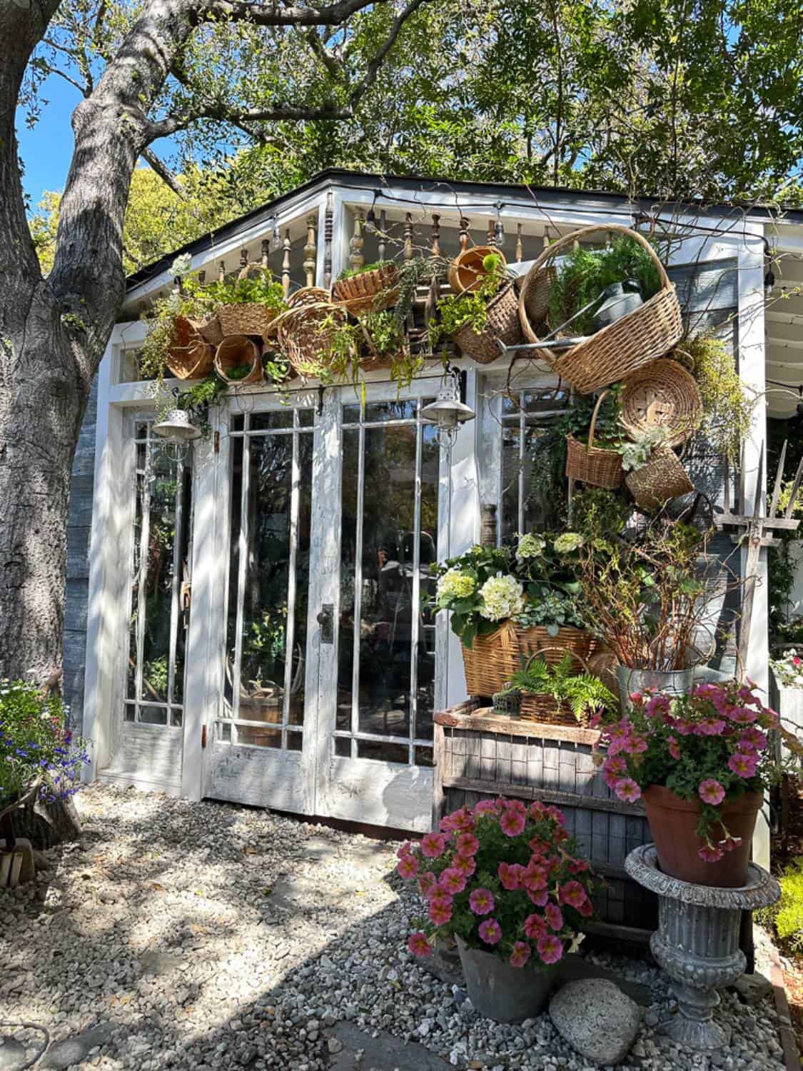 Full side view of summer She Shed with basket arch decor and planters with flowers