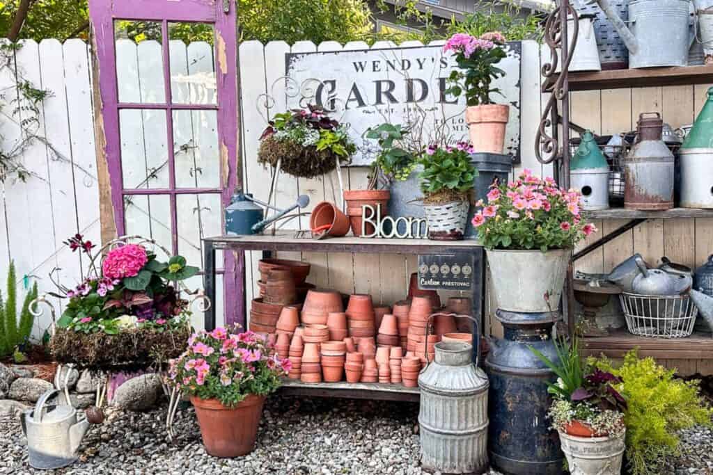 A workbench decorated with garden pots, plants, planted chairs, and more.