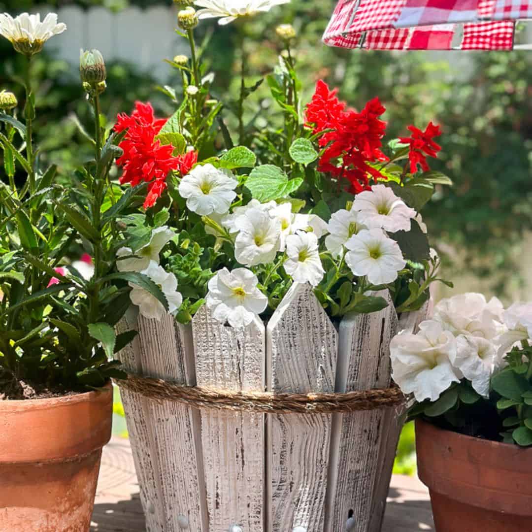 Picket flower pot with red and white flowers.