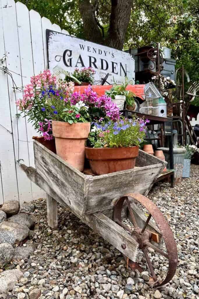 California Backyard Living-Vintage wheel barrow filled with pots of flowers.
