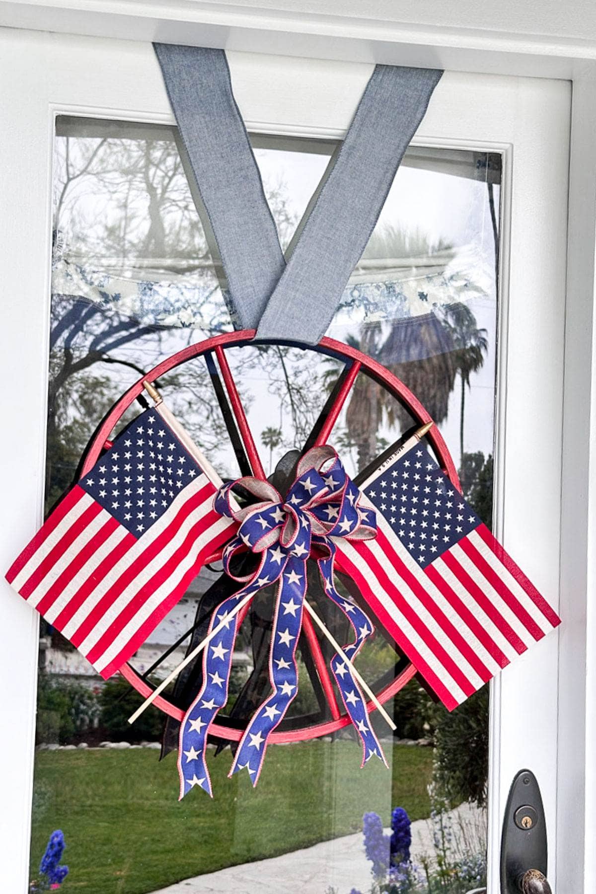 A wood wagon wheel wreath hanging on the front door. 