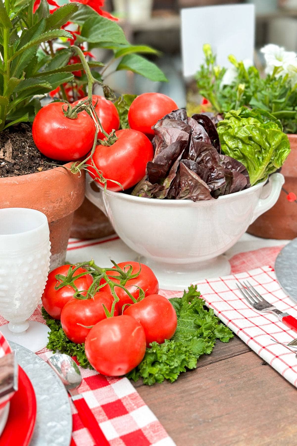 A bowl of lettuce and tomatoes decorate the table in addition to the other centerpiece.