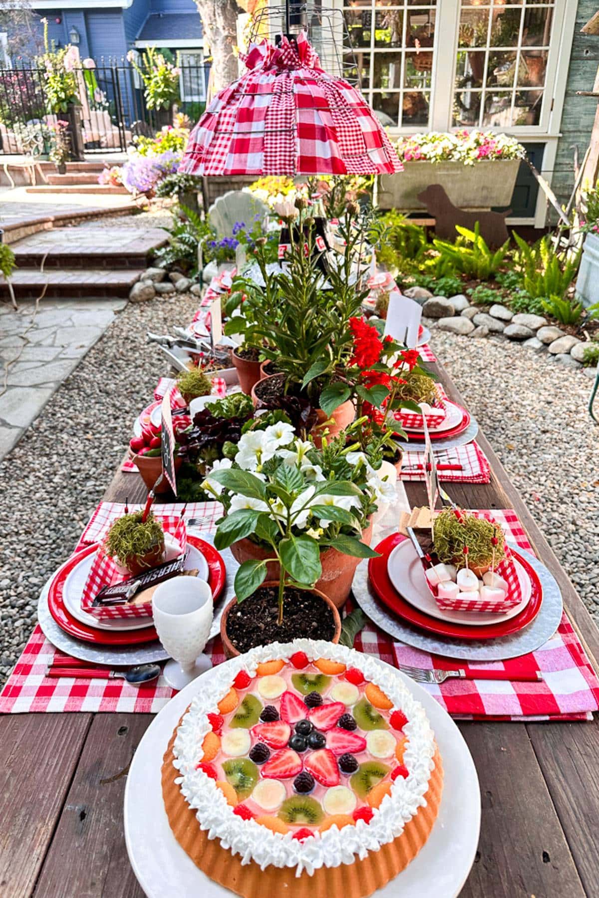 A VIEW OF MY SUMMER TABLESCAPE WITH FRUIT TARTS, SMORES, AND LOTS OF RED AND WHITE DECORATIONS. THE TABLE IS SET WITH FRESH HERBS, VEGETABLES AND FRUIT .