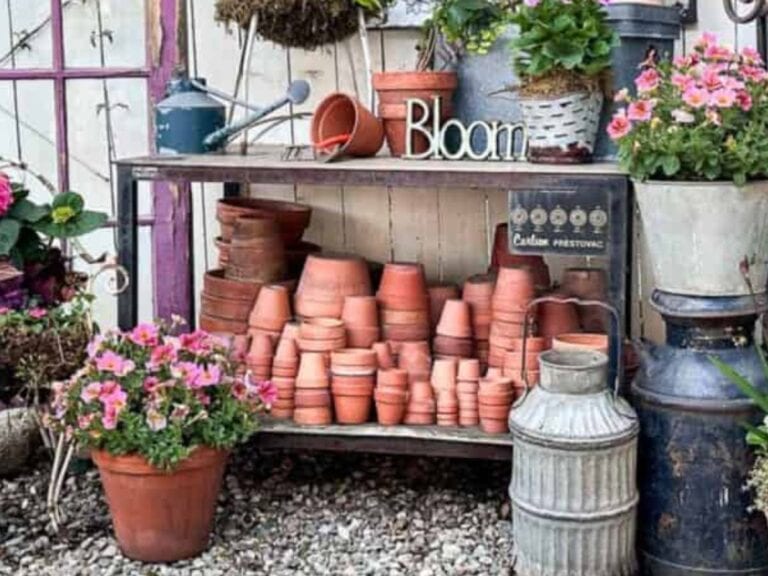 Scene of a thrifted garden table that is filled with red clay pots and vintage treasures.
