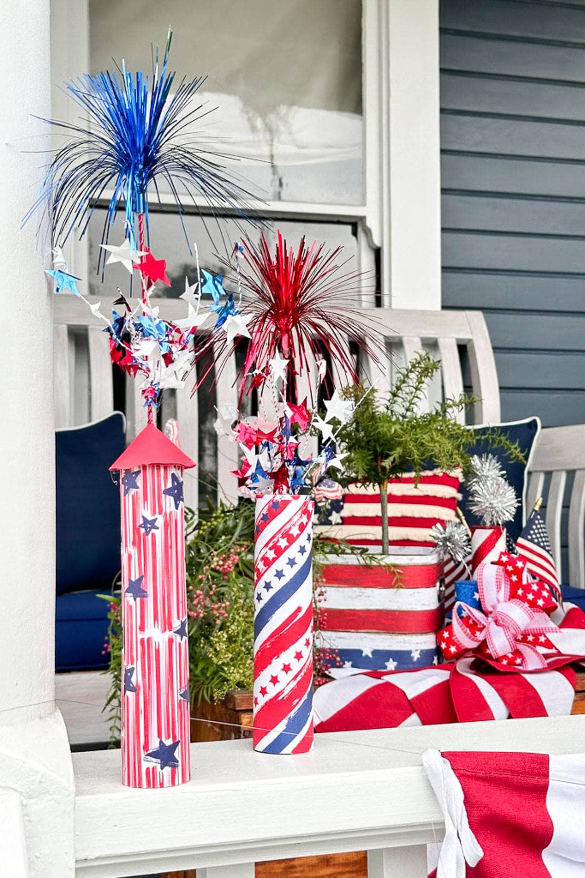 Paper firecrackers are sitting on the wood railing of the porch for an American porch decoration. 