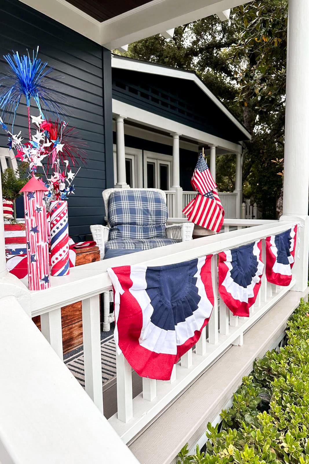 Decorating the front porch with American Flags and patriotic red, white, and blue buntings hanging on the railing 