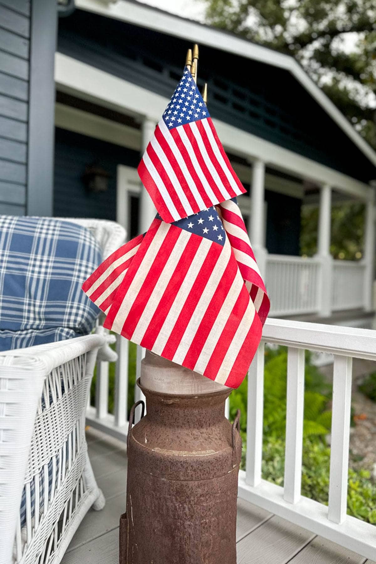 Flags in a vintage milk can sitting on the front porch. 