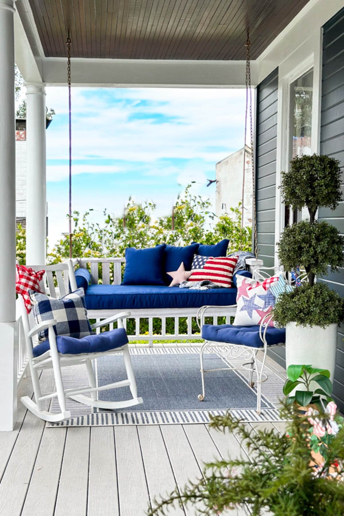 An All-american front porch decorated for the fourth of July with a porch swing.