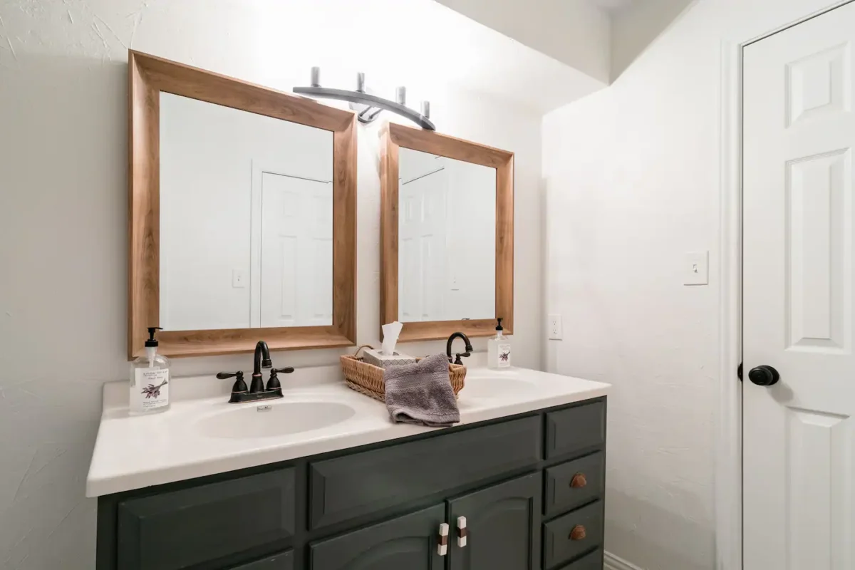 Grey and white airbnb bathroom with gold mirrors 