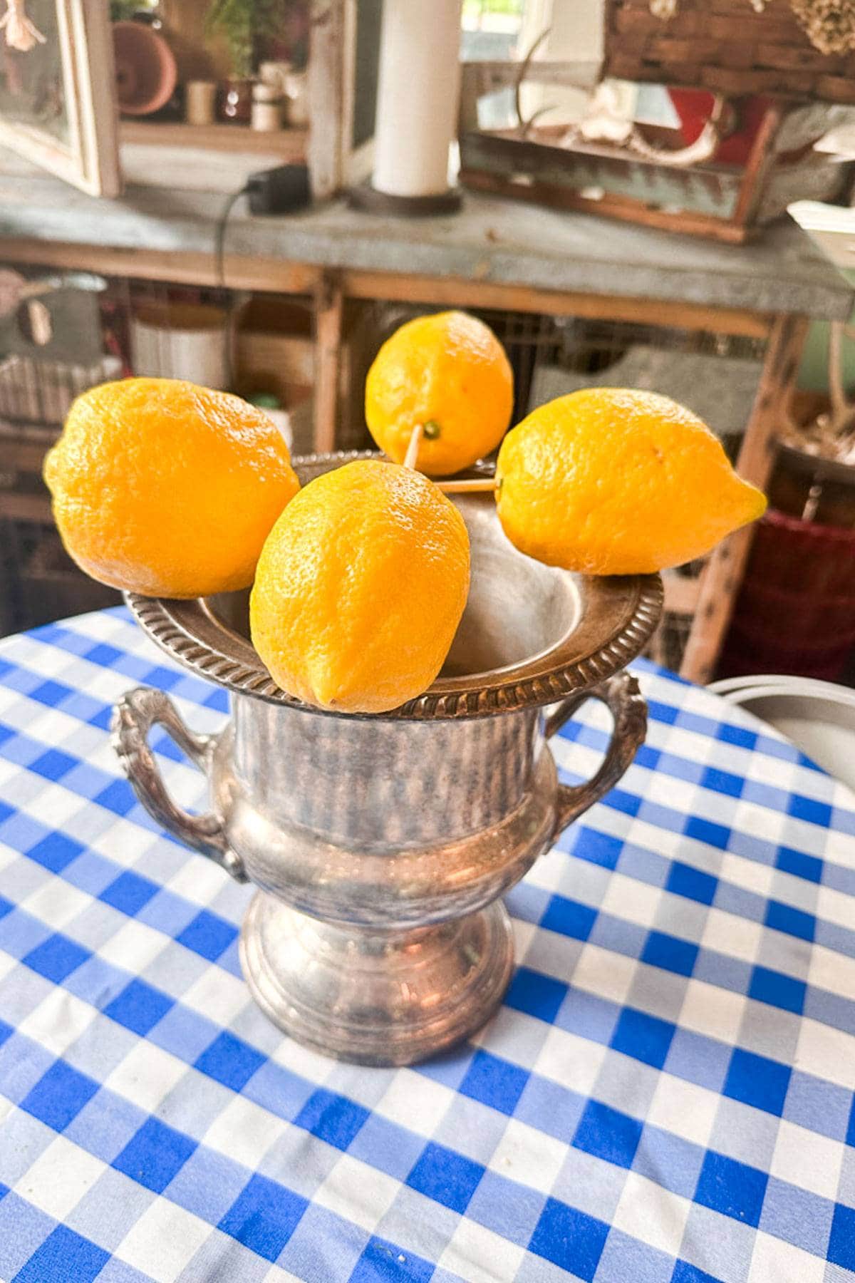 4 lemons are sitting on top of a vintage silver wine bucket in the process of making a DIY lemon centerpiece. 