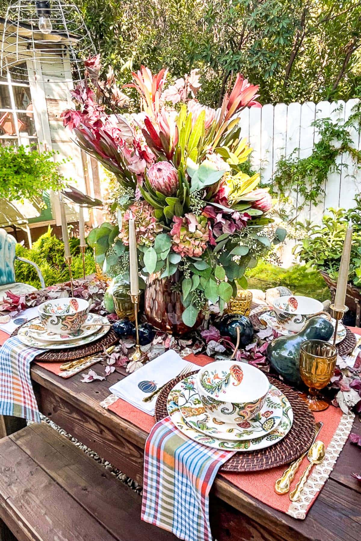 fall tablescape ideas with a large floral centerpiece, colorful plaid napkins, and gourds