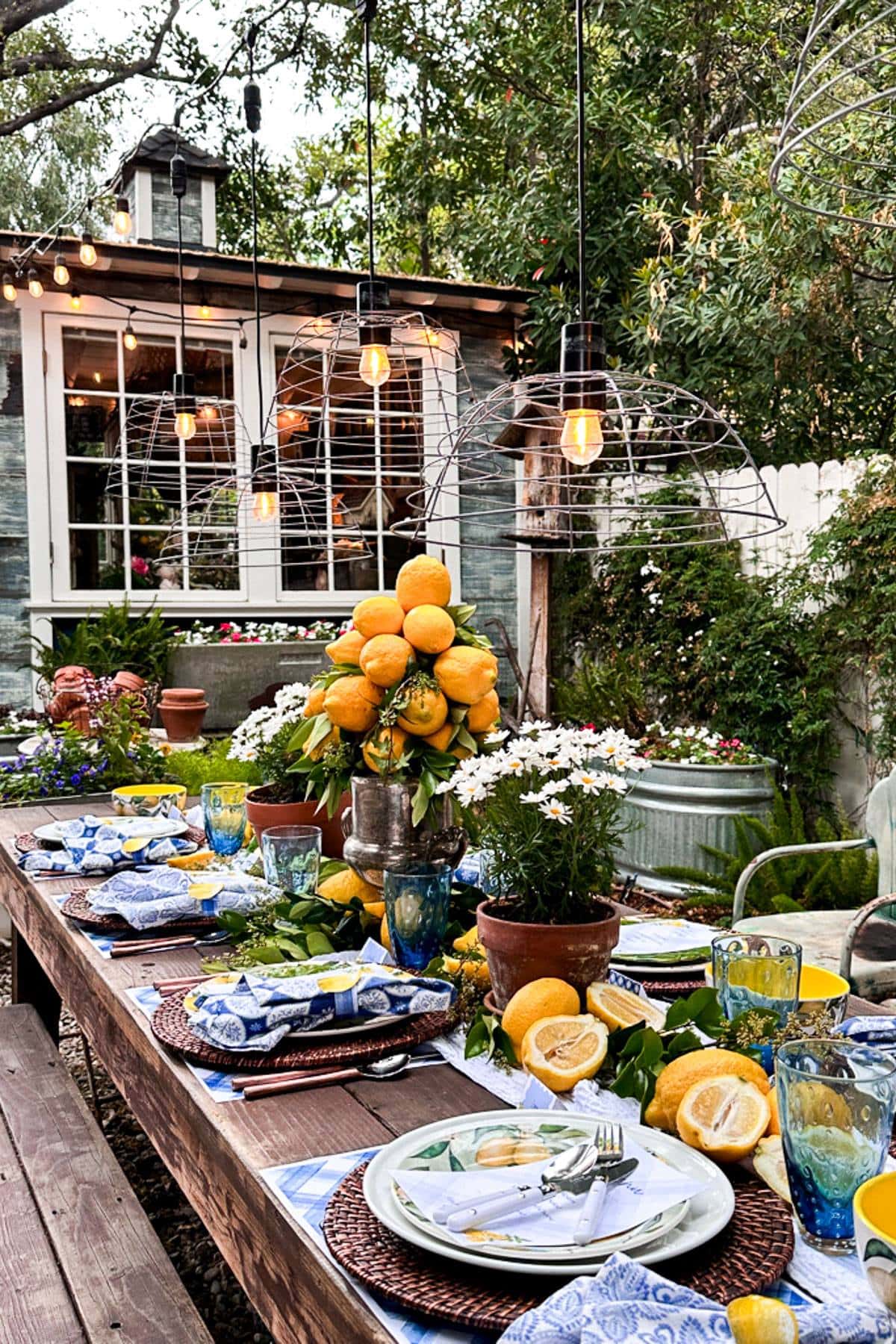 Summer tablescape with lemons set in the garden at dusk with the DIY garden basket lights on