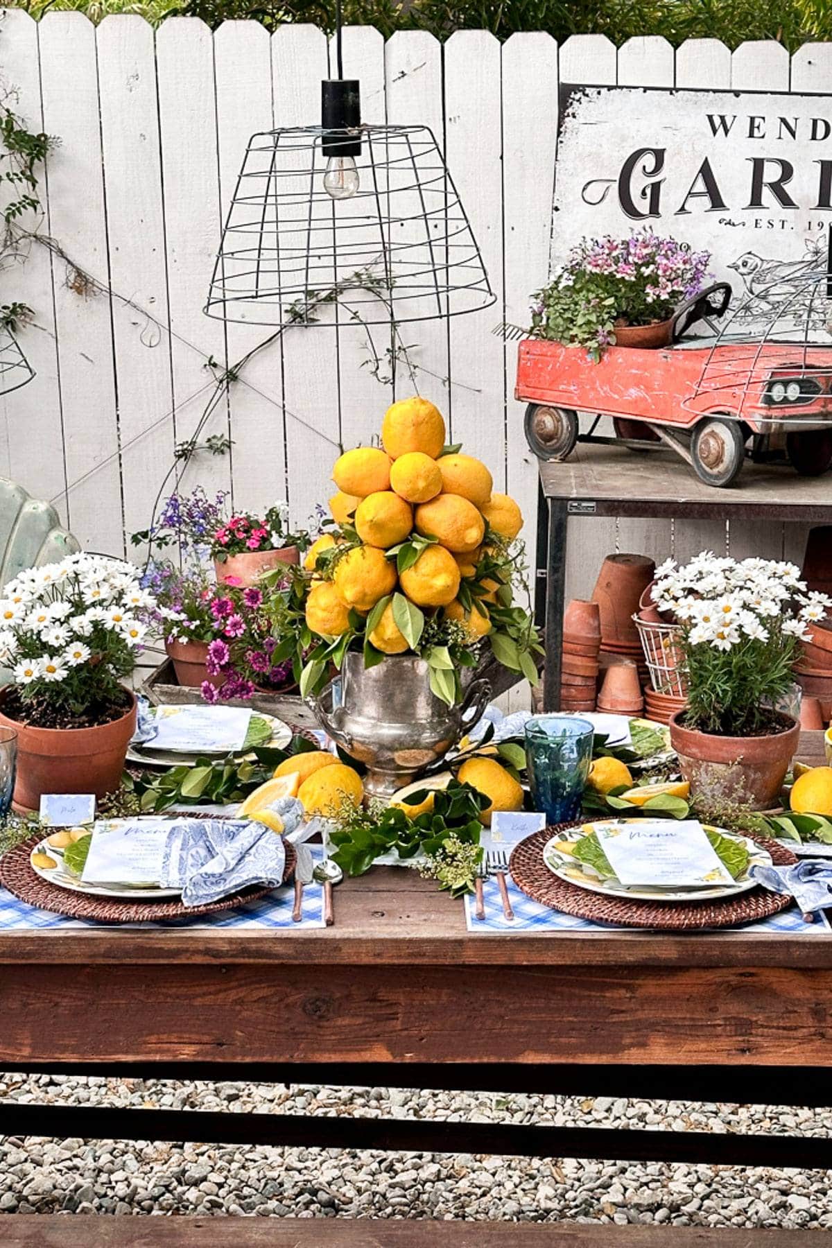 Lemon centerpiece and potted daisies on a summer tablescape set outdoors in the garden