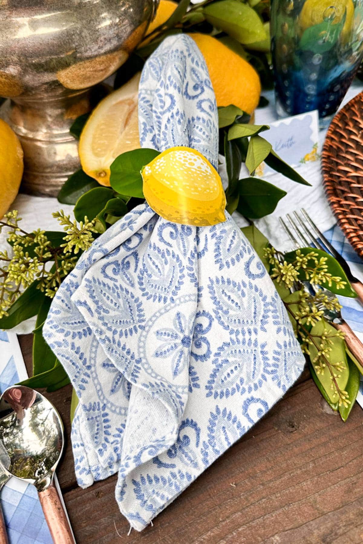 Free printable paper lemon napkin ring wrapped around a blue and white block print napkin