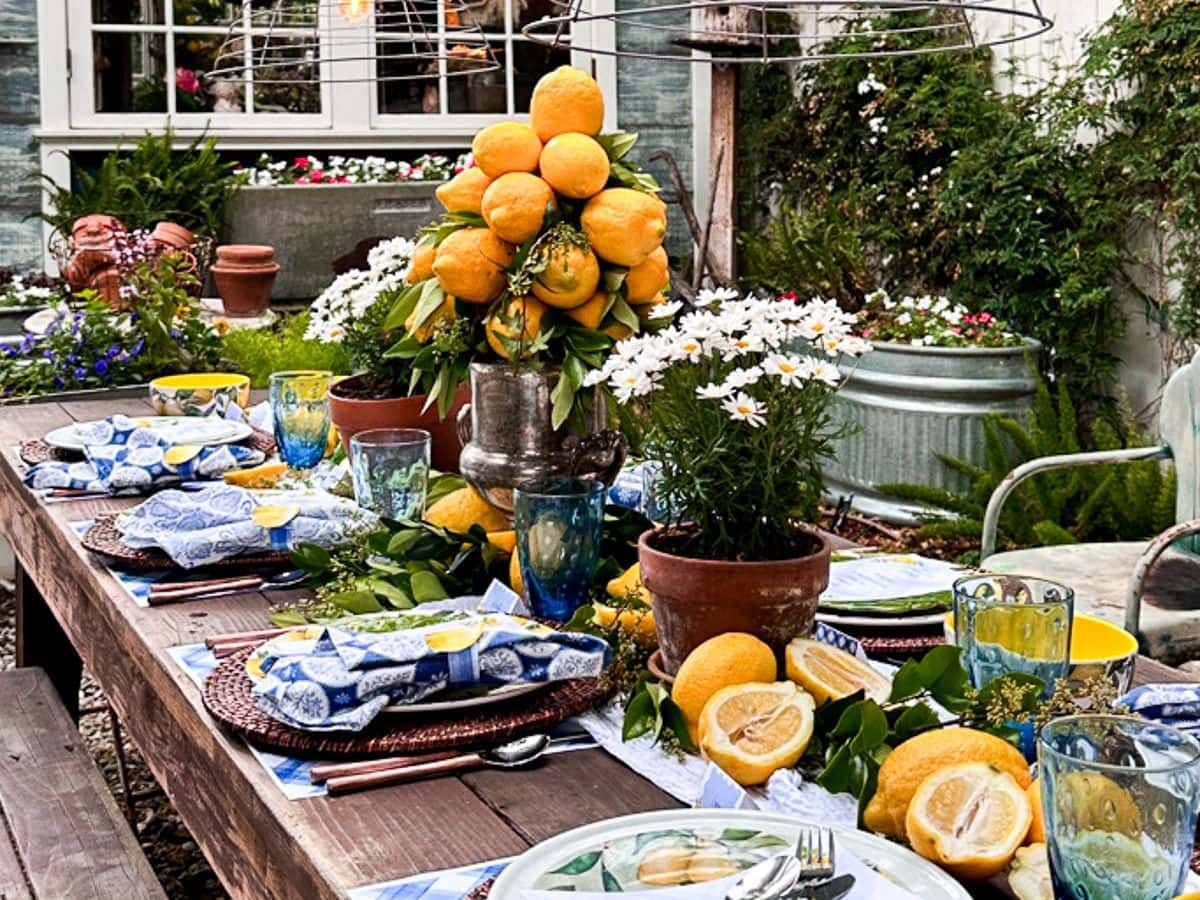 Summer tablescape with lemons set in the garden at dusk with the DIY garden basket lights on