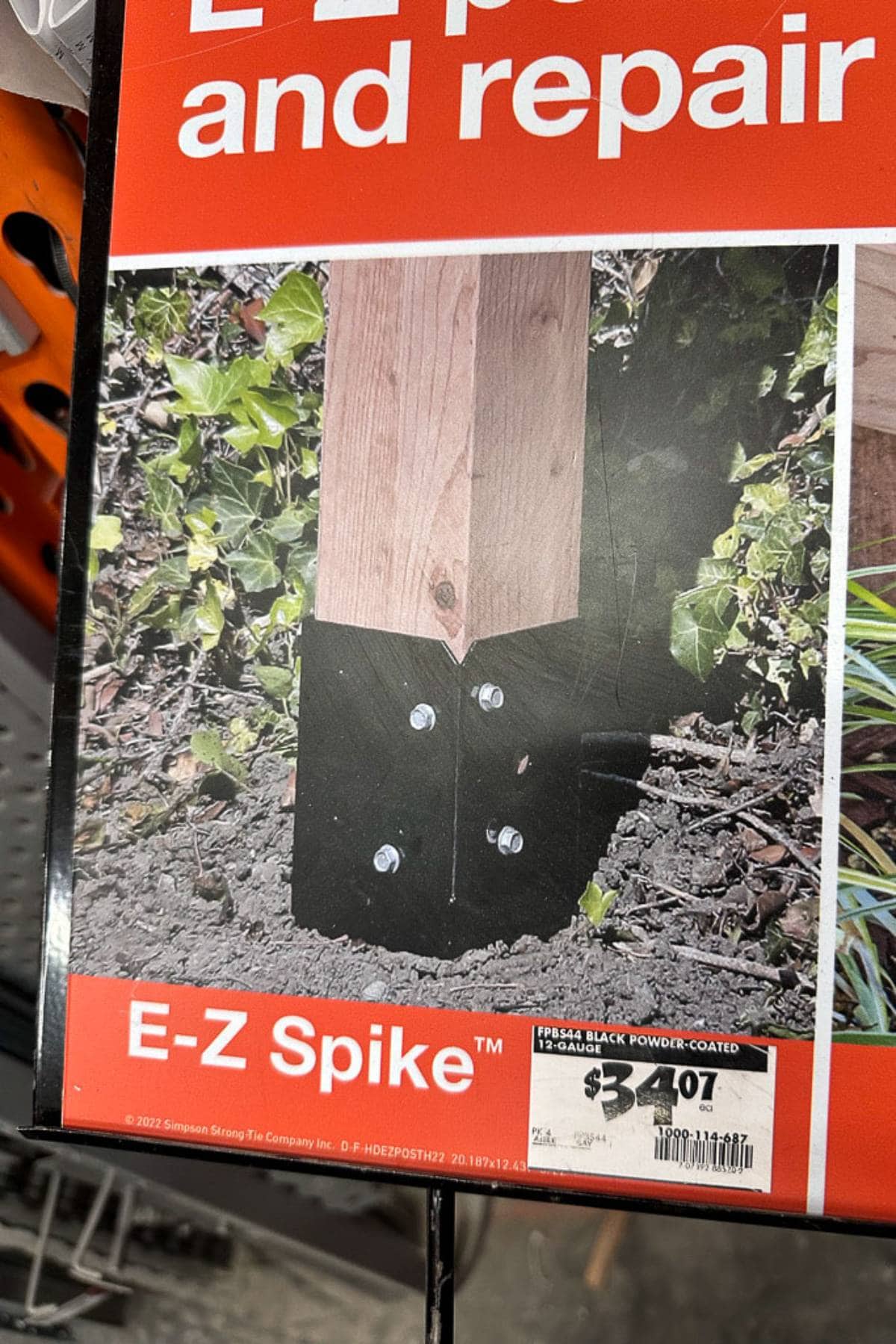 A product display featuring the E-Z Spike for fence construction and repair. The image shows a wooden post secured in the ground with a black powder-coated metal spike priced at $24.97, from Simpson Strong-Tie Company.