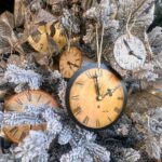 A Christmas tree decorated with various vintage clocks and glittery ornaments. The tree is dusted with faux snow, creating a wintry effect. Each clock shows a different time, adding a whimsical touch to the festive display.