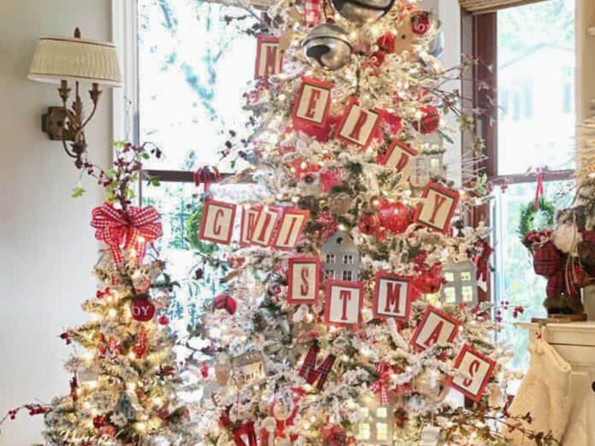 A beautifully decorated Christmas tree with white and red ornaments dazzles, while a banner elegantly spells "Merry Christmas" across its branches. Nearby, smaller trees echo the theme, creating a harmonious and festive holiday ambiance.