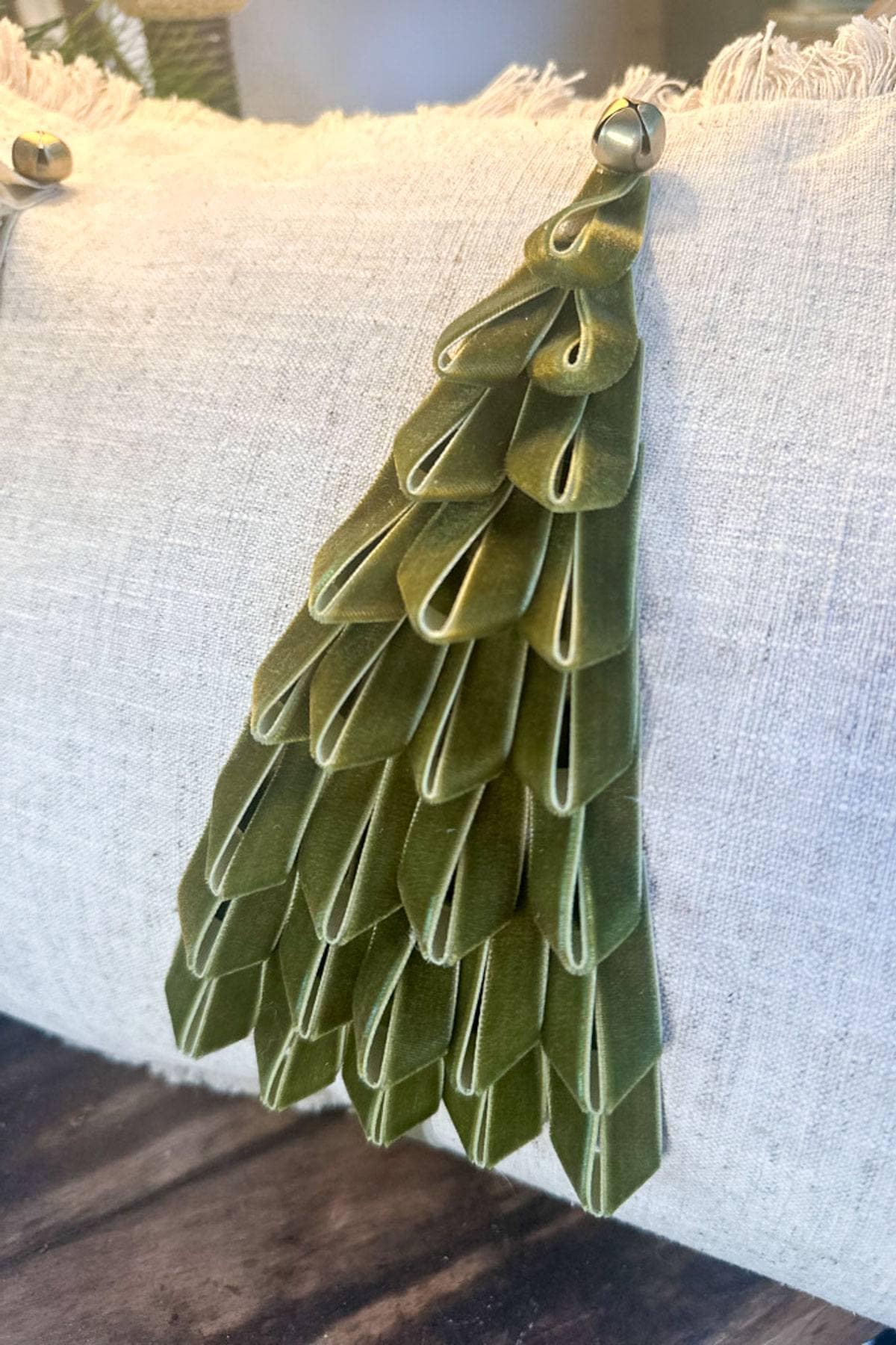 Close-up of a decorative pillow featuring a green velvet Christmas tree design.