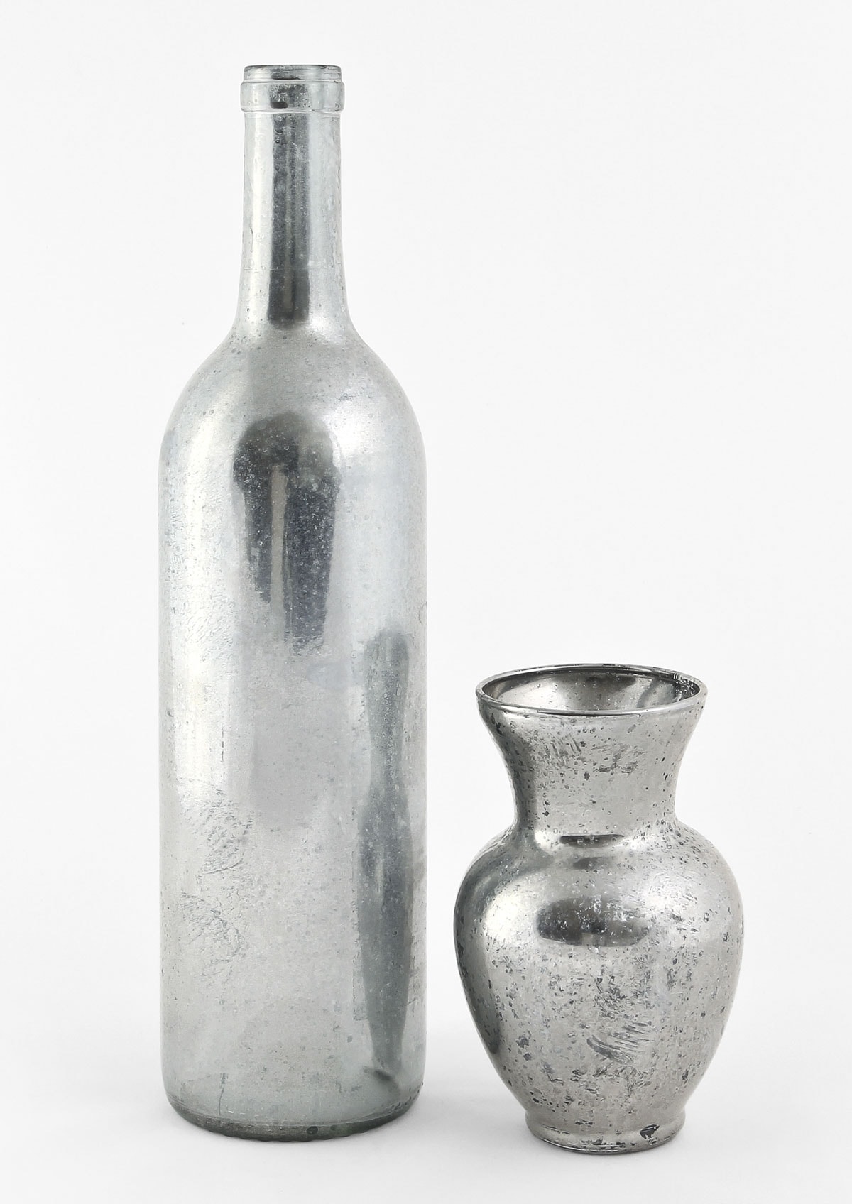 diy mercury glass ornaments- A tall, slender bottle and a smaller, round vase, both made of distressed, textured metal, are placed side by side against a plain white background. The bottle has a narrow neck, while the vase has a flared opening.