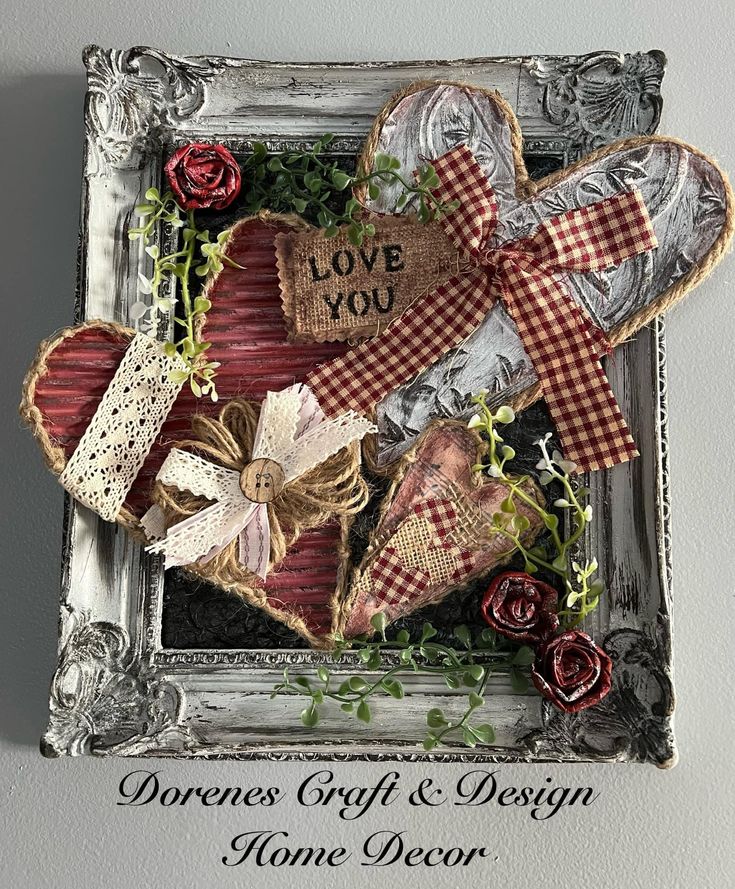 A decorative frame featuring various heart shapes made of burlap and fabric, with bows and lace, embodies the charm of Valentine Decor. Red roses and green vines accent the design. The central heart reads "LOVE YOU." Text at the bottom states "Dorene's Craft & Design Home Decor.