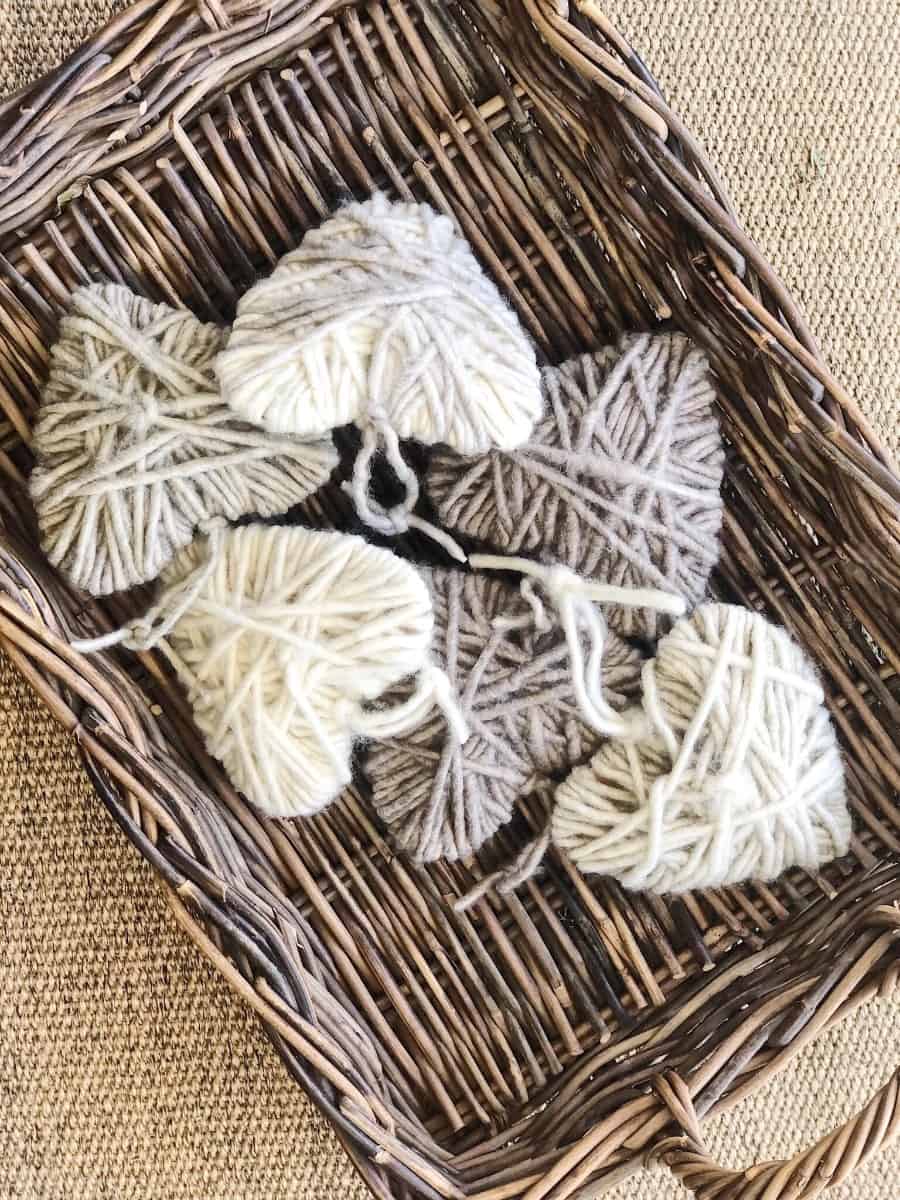 A delightful wicker basket adorns the She Shed, filled with yarn-wrapped hearts in shades of white, cream, gray, and brown. Set on a textured surface, these hearts are meticulously arranged to showcase diverse yarn patterns—a perfect piece for Sunday Sharing: Volume 33.