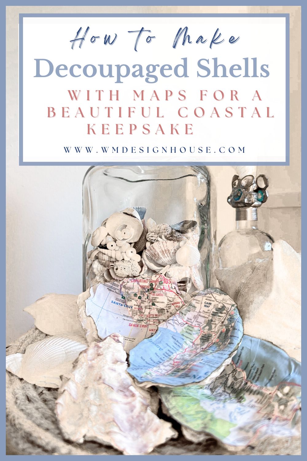 A glass jar filled with assorted seashells sits next to a decoupaged shell with a map design. Nearby are more shells, a glass bottle with a shell stopper, and a decorative rope, creating a coastal-themed display.