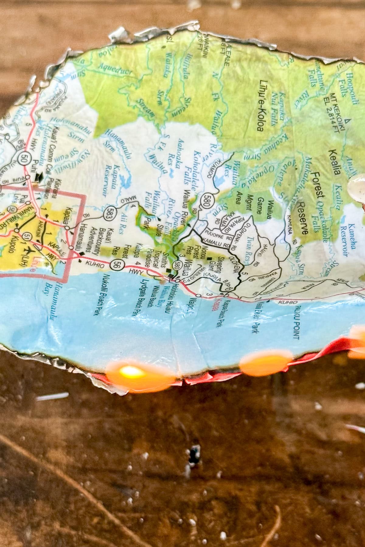 A close-up of a curved map showing parts of southern Mexico, including Oaxaca and Chiapas, with a few small orange lights along the map’s lower edge on a wooden surface.