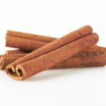 Three rolled cinnamon sticks rest on top of two more cinnamon sticks against a plain white background, creating a cozy scene reminiscent of DIY Sweater Pears crafts.
