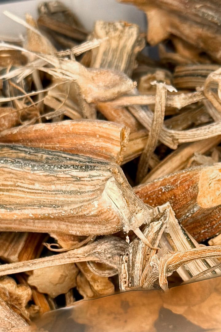 Close-up of dry pumpkin stems, revealing rough textures and layers of brown, beige, and tan. The fibrous stems are tangled and loosely piled together—ideal for unique pumpkin stem crafts.