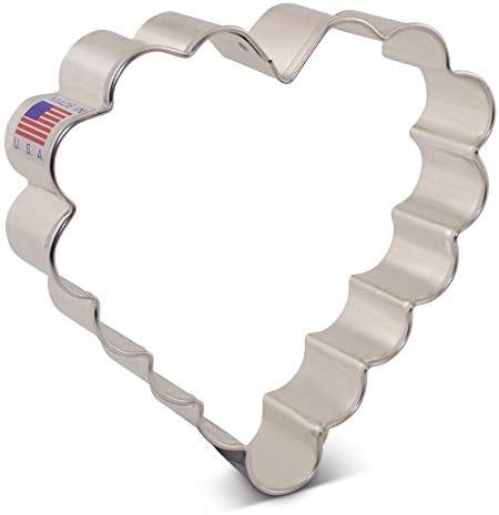 A metal cookie cutter shaped like a scalloped heart, perfect for making Heart Sugar Cookies, with a small USA flag sticker attached to one side.