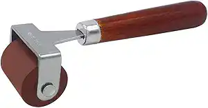 A brown rubber roller with a sturdy wooden handle and a metal bracket connecting the roller to the handle, commonly used for arts, crafts, printmaking, or vegetable block printing.