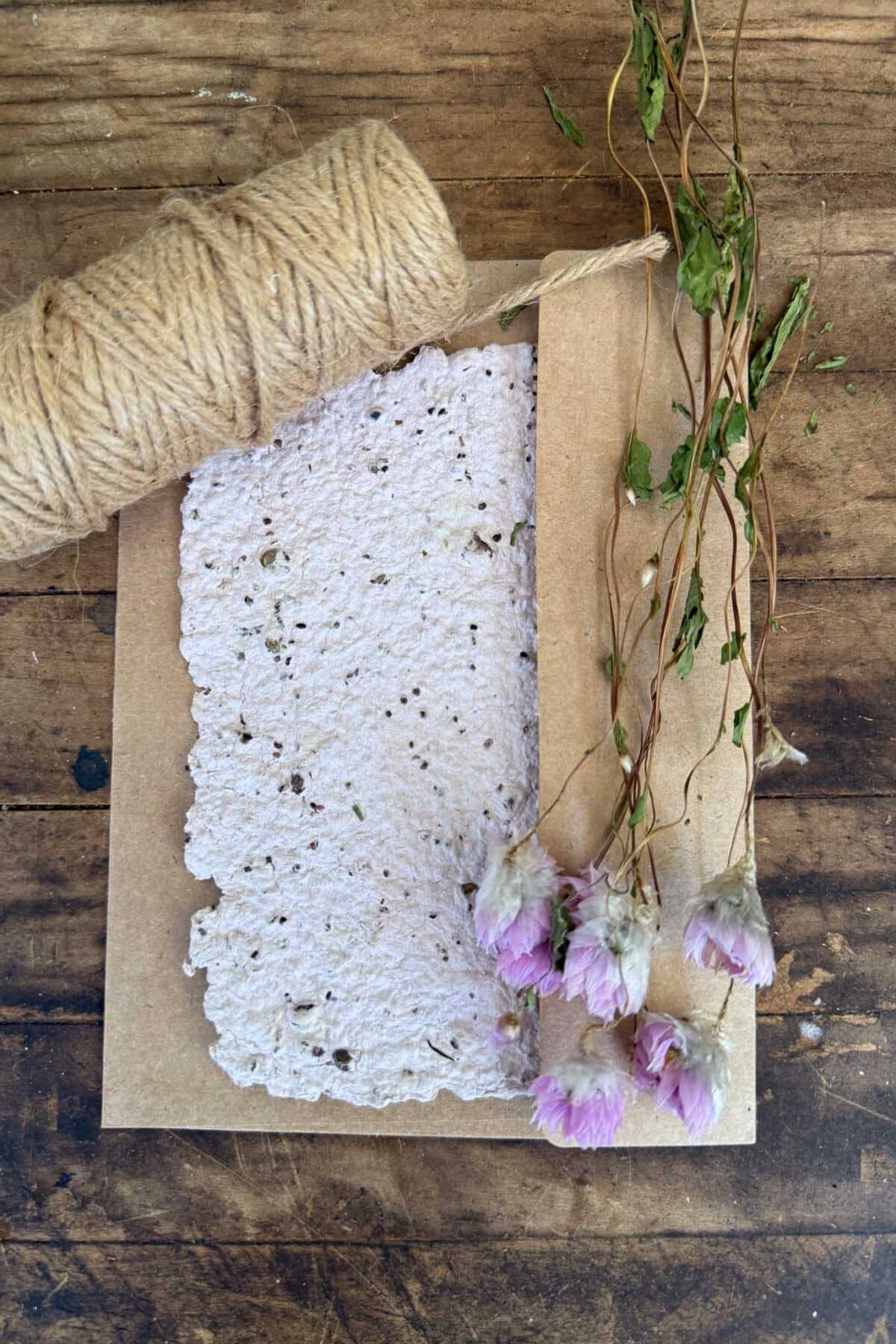 Rustic handmade soap with dried purple flowers and green foliage on wooden background.