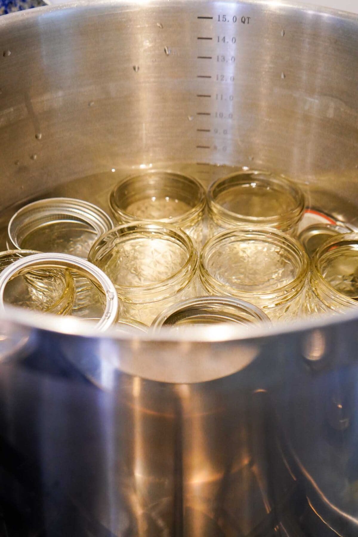 Sterilizing glass jars in a large stainless steel pot for home canning and food preservation.