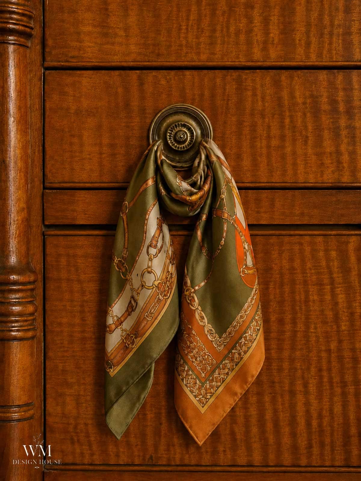 A patterned silk scarf in green, orange, and gold hues hangs from an ornate round drawer pull on a wooden dresser, adding a touch of fall bedroom decor and inspiring cozy bedroom ideas for a seasonal refresh.