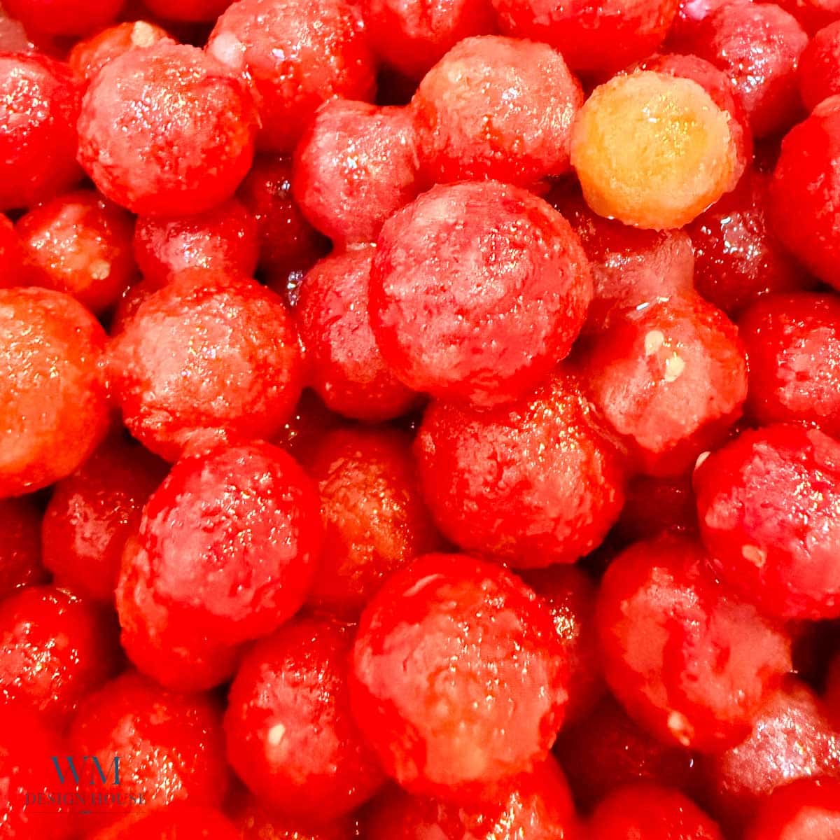 A close-up of many round red watermelon balls, glistening with moisture, piled together.
