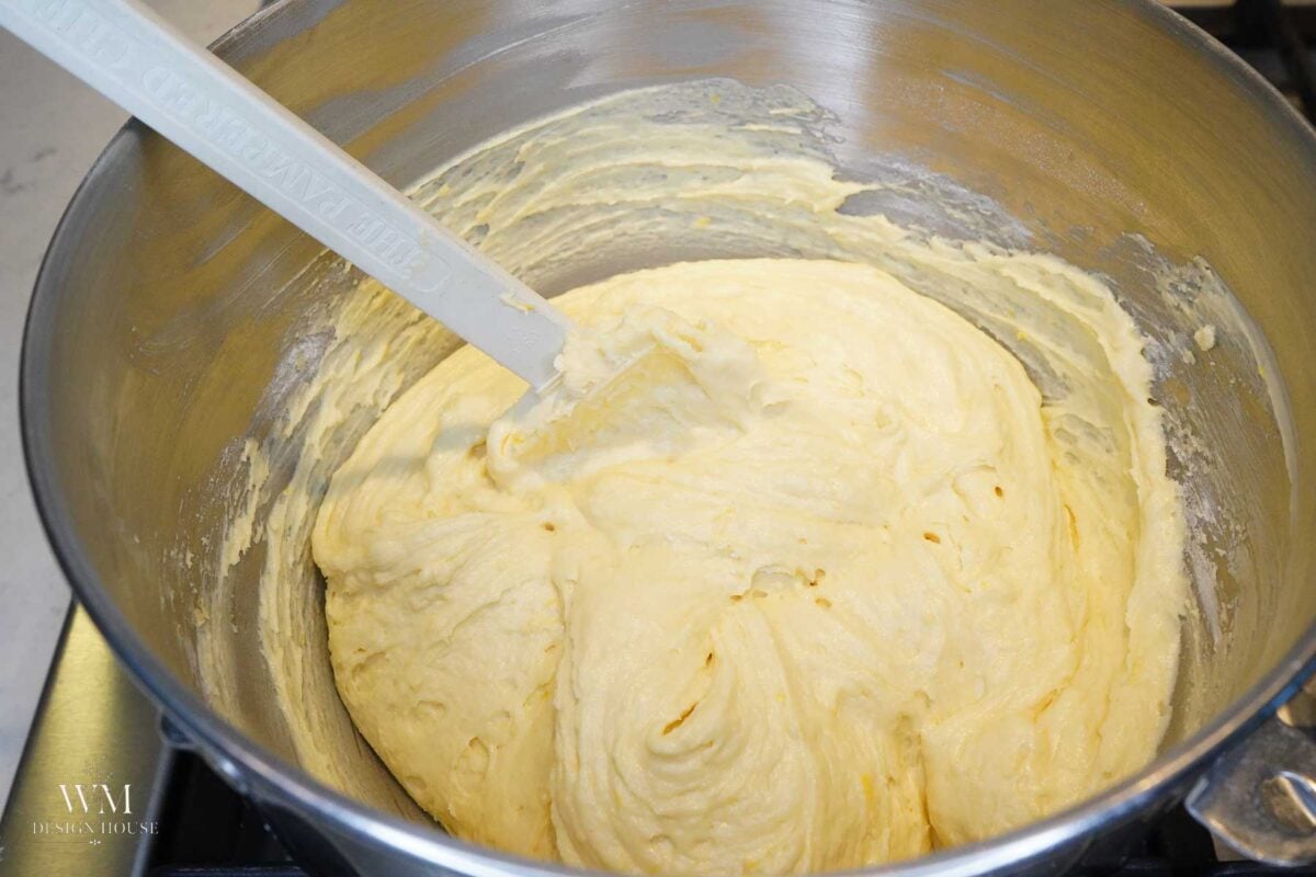 Smooth, pale yellow lemon cake batter in a stainless steel mixing bowl with a spatula