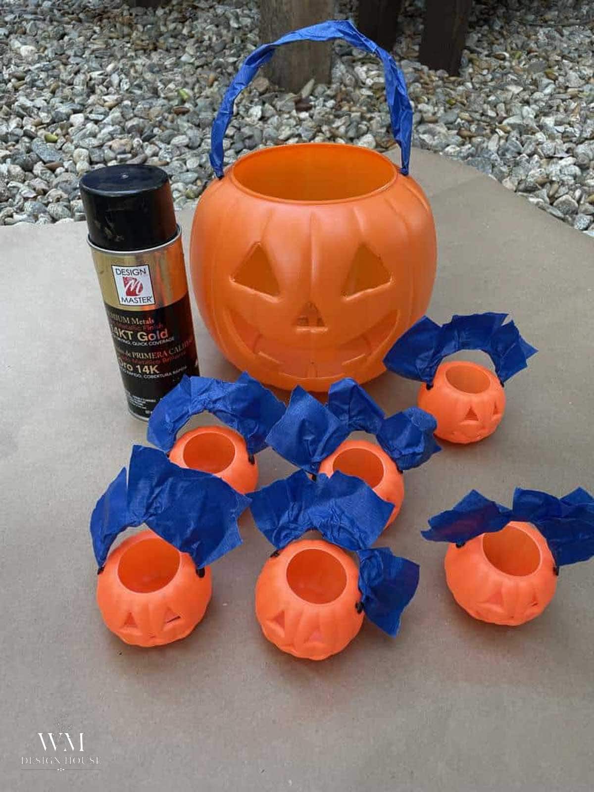 Plastic pumpkin bucket with the handle wrapped in painter's tape before spray painting