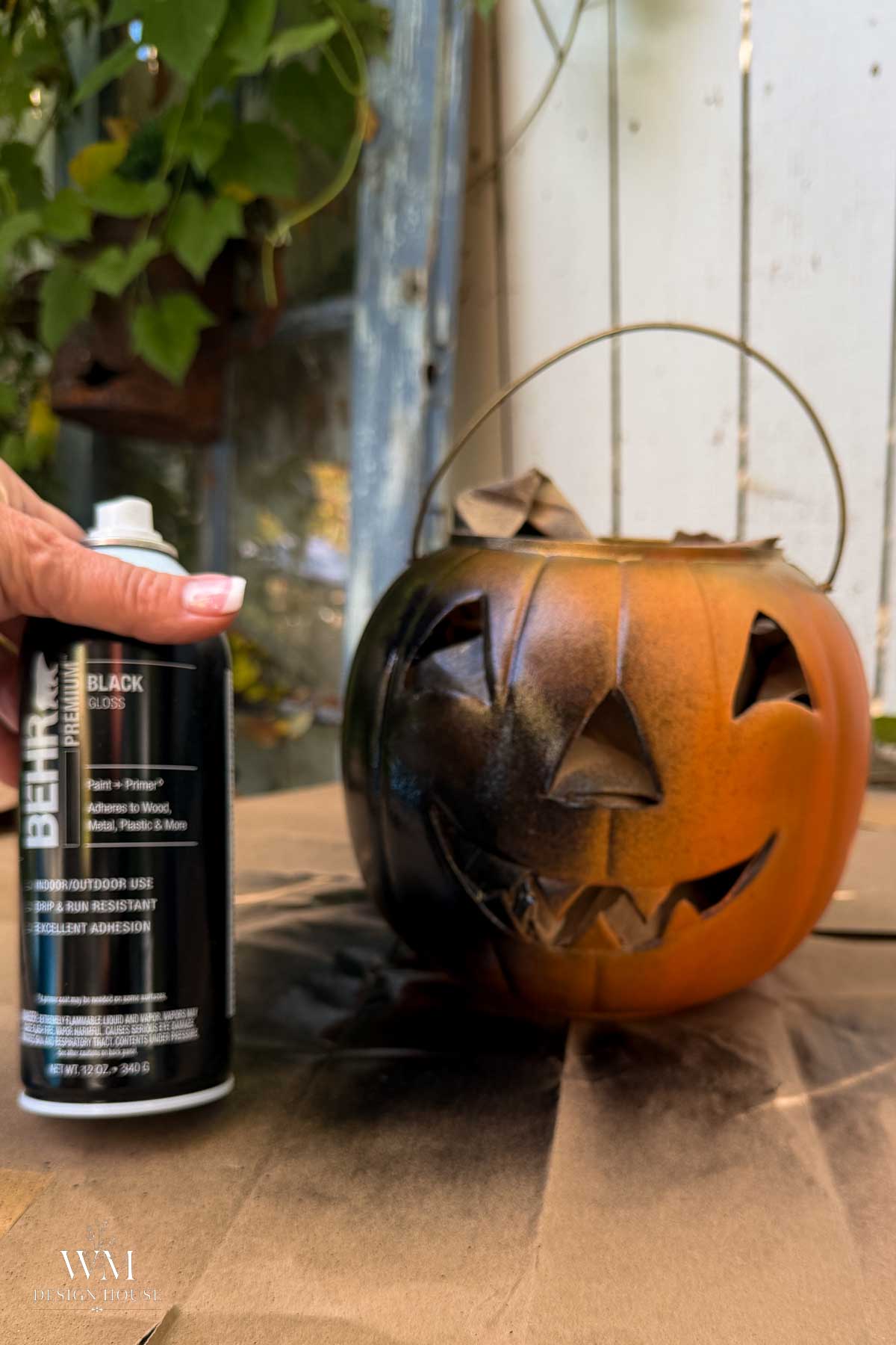 Plastic pumpkin buckets painted matte black drying on brown paper. 