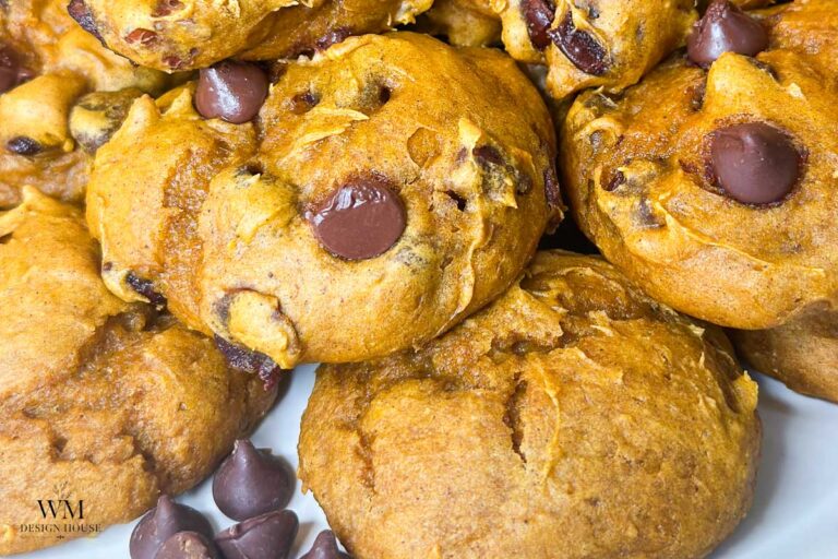 Close-up of freshly baked 3 ingredient pumpkin cookies piled together, with visible chocolate chips and a golden-brown, soft texture.