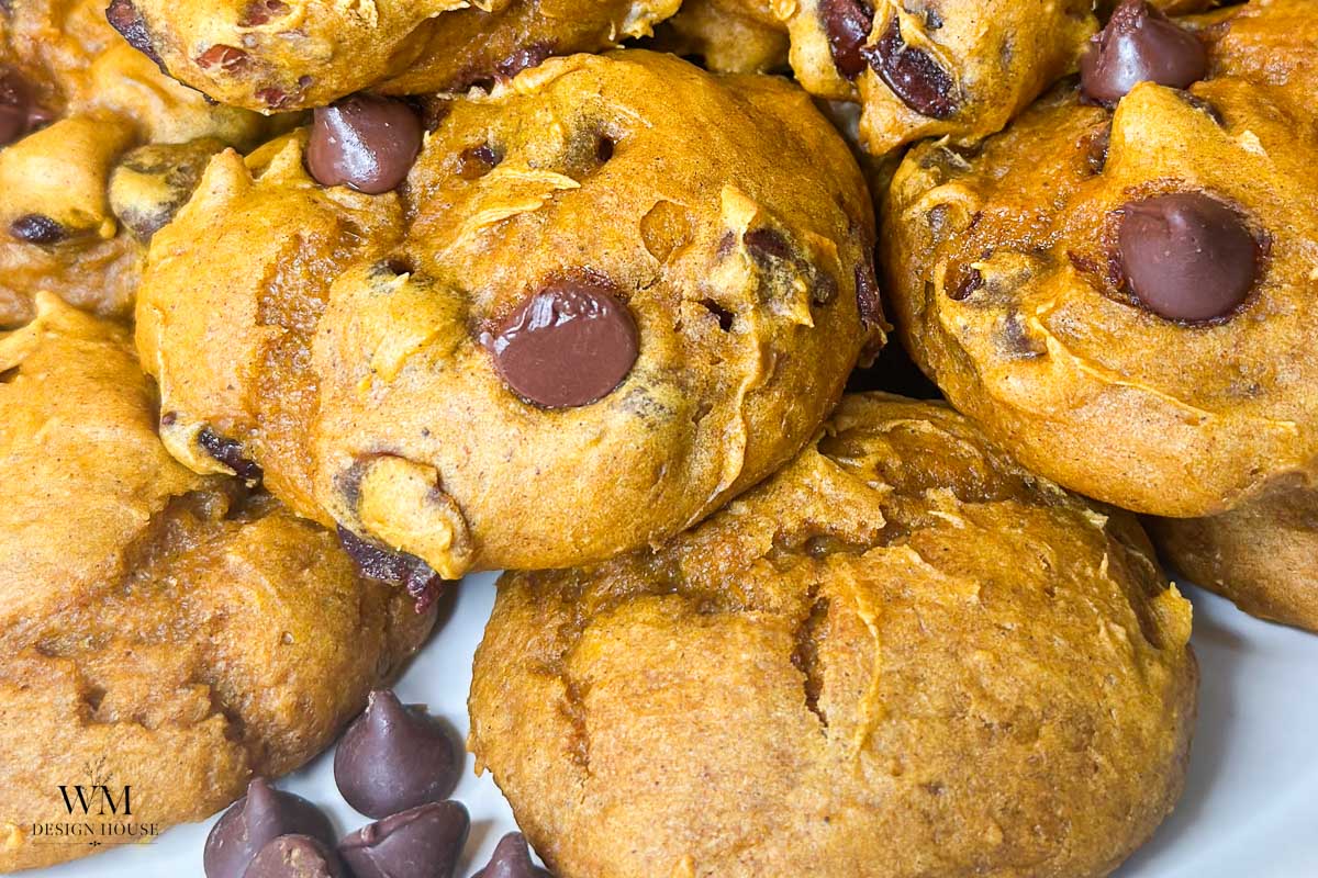 Close-up of freshly baked 3 ingredient pumpkin cookies piled together, with visible chocolate chips and a golden-brown, soft texture.